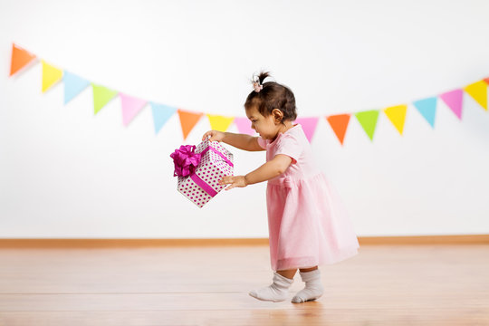 childhood, people and celebration concept - happy baby girl with gift box on birthday party
