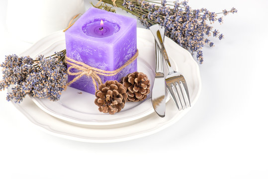 Still life with lavender candle, fir cones and dry lavender on a white plate on white background