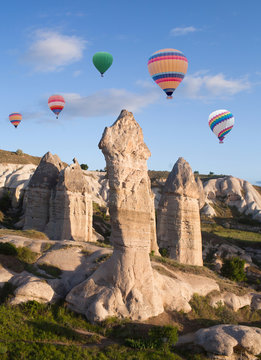 Colorful hot air balloons flying over unique geological formations in Cappadocia, Anatolia, Turkey