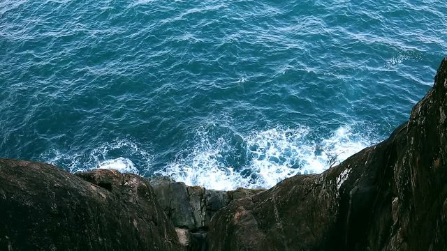 Waves on the Sea. Top view from the rocks of the Sea surface. Beautiful deep blue Ocean Water background. Black impregnable rocks