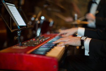 Close-up the elegant man playing the piano indoors