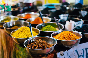 Indian spices in shiny metal bowls put for sale on a vendors table
