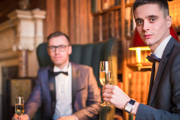 The young serious, elegant man sitting in restaurant and drinking a champagne