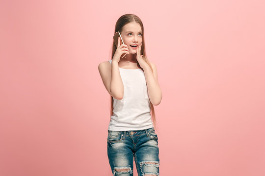 The happy teen girl standing and smiling against pink background.