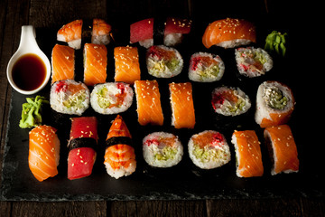 Sashimi and sushi rolls on a stone slatter. Sushi set with salmon, prawns, soy souce, wasabi and ginger. Traditional Japanese cuisine.