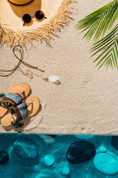 top view of various female accessories on sandy beach