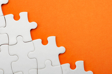 Obraz premium Jigsaw puzzle pieces and business concept with a border made of puzzle pieces on colorful bright orange background with copy space