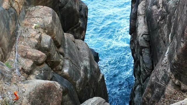 Waves on the Sea. Top view from the rocks of the Sea surface. Beautiful deep blue Ocean Water background. Black impregnable rocks