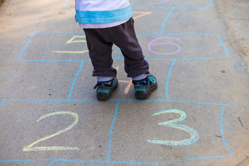 Hopscotch in a schoolyard on an asphalt floor with chalk drawings of numbers and squares as an icon...