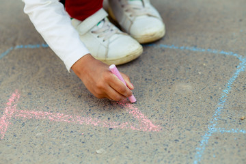 Hopscotch in a schoolyard on an asphalt floor with chalk drawings of numbers and squares as an icon of youth innocence and children playing a fun jumping game at recess or after elementary school.