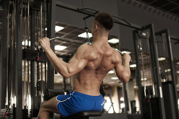 Fototapeta na wymiar Athlete muscular bodybuilder training back on simulator in the gym