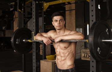 Fototapeta na wymiar Healthy young man standing strong in the gym and flexing muscles - muscular athletic bodybuilder fitness model posing after exercises