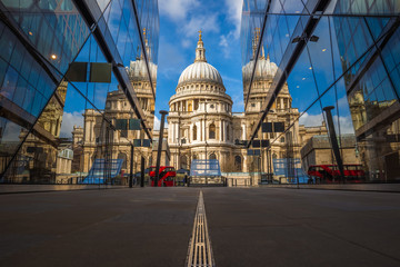 London, England - Beautiful St.Paul's Cathedral reflected in glass windows in the morning sunlight with iconic red double-decker bus and blue sky - obrazy, fototapety, plakaty