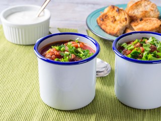 Russian beetroot soup borscht in enamel mugs on green cloth