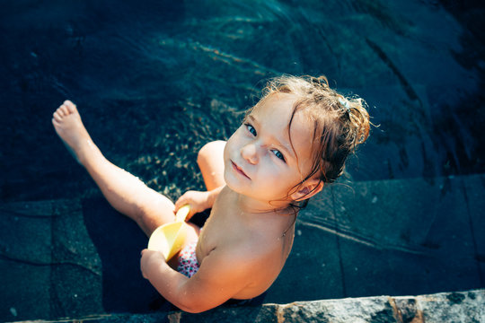 Kind im Pool schaut nach oben in die Kamera