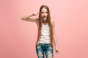 The happy teen girl pointing to you, half length closeup portrait on pink background.