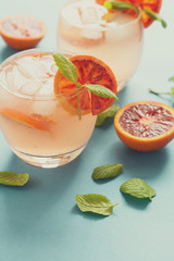 Blood orange cocktail with slices of orange on turquoise background. Toned