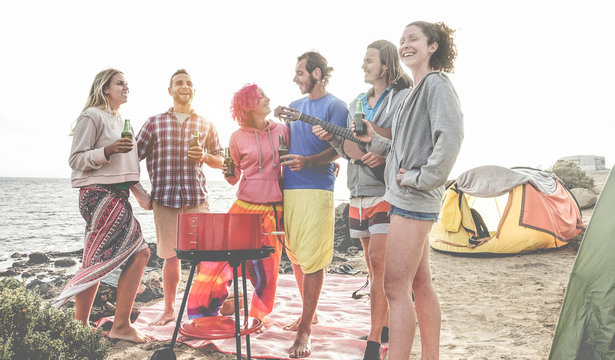 Happy friends drinking beers at camping barbecue picnic next to the ocean - Surfers people having fun and laughing together during summer party holidays - Travel, vacation and friendship concept