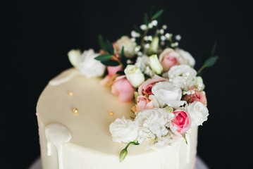 Beautiful Wedding cake with flowers on  table and black background, selection focus