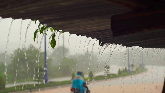 Slowmotion shot of a heavy rain and water faling from a roof of a building.