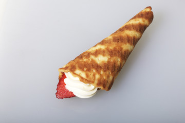 Waffle horns with cream, decorated with strawberries.