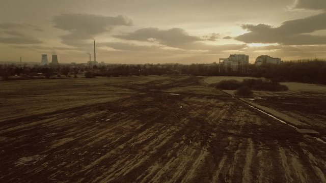 Drone shot of urban industrial landscape with meadows and power plant on the horizon.
