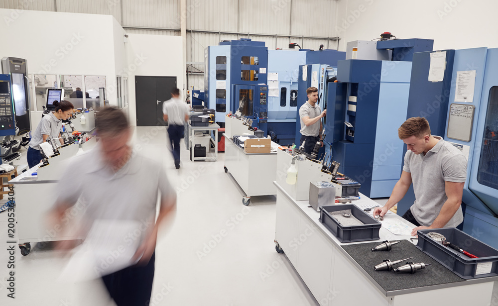 Wall mural busy engineering workshop with workers using cnc machinery