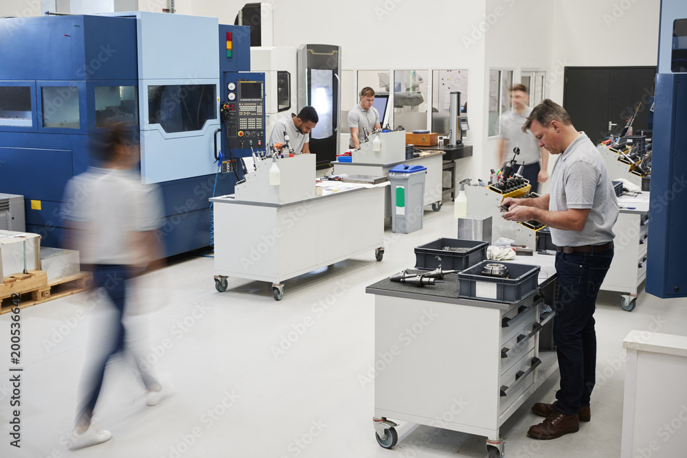Wall mural busy engineering workshop with workers using cnc machinery