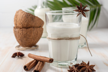 Shell of coconut and coconut milk in glass with cinnamon on wooden table.