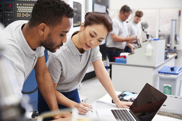 Two Engineers Using CAD Programming Software On Laptop
