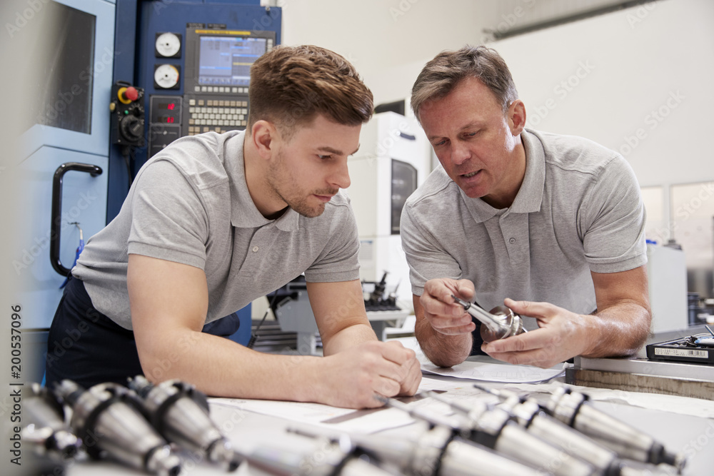 Wall mural engineer showing apprentice how to measure cad drawings