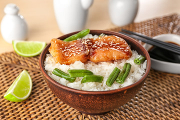 Fish fillet served with rice and green beans on wicker coaster