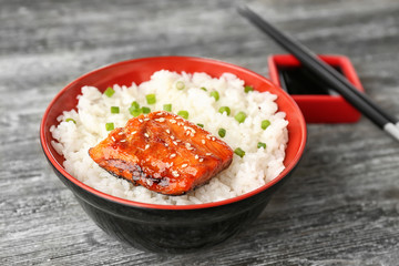 Fish fillet served with rice in bowl on grey background