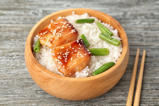 Fish fillet served with rice and green beans in wooden bowl on grey background