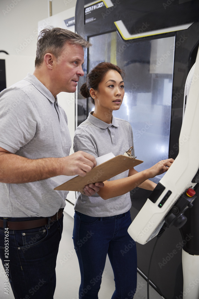 Wall mural engineer training female apprentice to use cnc machine in factory