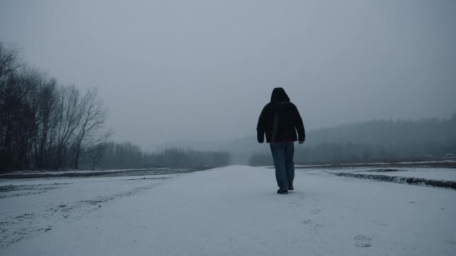Man walking on an empty road in winter. 