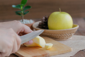 Woman use knife kitchen to chopped or cut and sliced fresh Shinano gold apple on wood cutting board for snack and salad or prepare for homemade apple pie for family. Home cooking concept.