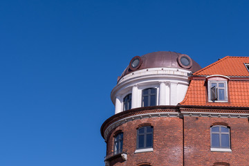 Fototapeta na wymiar A large rounded building turret, with rounded skylights a decorative columns under a blue sky. the adjoining window is open.