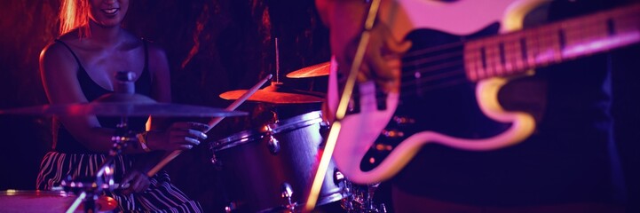 Man playing guitar with female drummer in nightclub