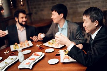 Meeting with japanese businessmen in restaurant. Men are eating sushi and talking.