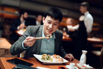 Meeting with chinese businessmen in restaurant. Man is eating sushi.