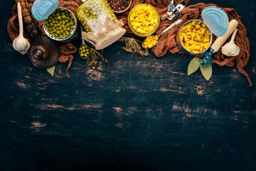 Marinated peas and corn in a jar. Stocks of food. Top view. On a wooden background. Copy space.
