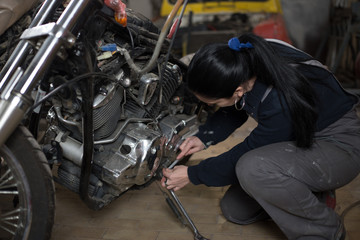 Girl worker in motorcycle repair shop