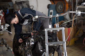 Fototapeta na wymiar Girl worker in motorcycle repair shop