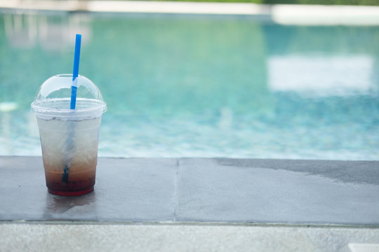 Soda with ice at the edge of a pool