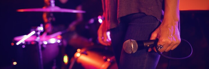 Female singer holding microphone with drummer performing in