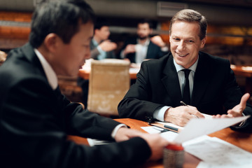 Meeting with chinese businessmen in restaurant. Men are discussing points in documents.