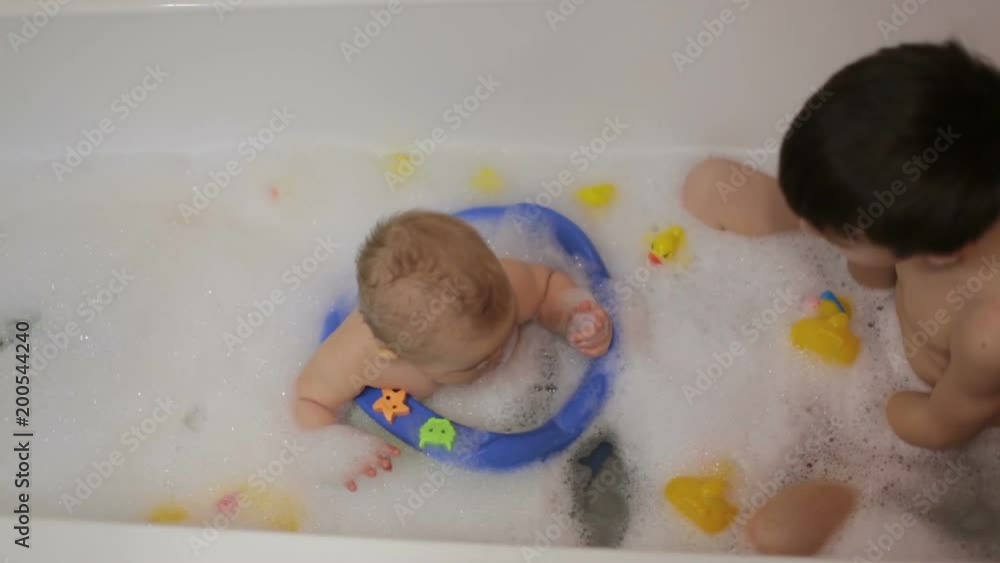 Wall mural Little baby boy, playing with rubber ducks in bathtube with his siblings