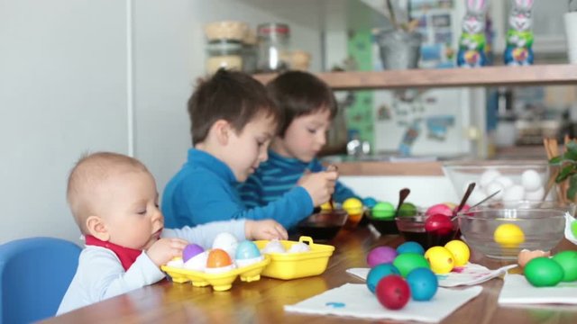 Three children, coloring and painting easter eggs at home for the holiday