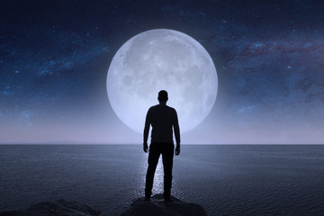 A man looks at the stars and the moon.  Elements of this image furnished by NASA. - Powered by Adobe